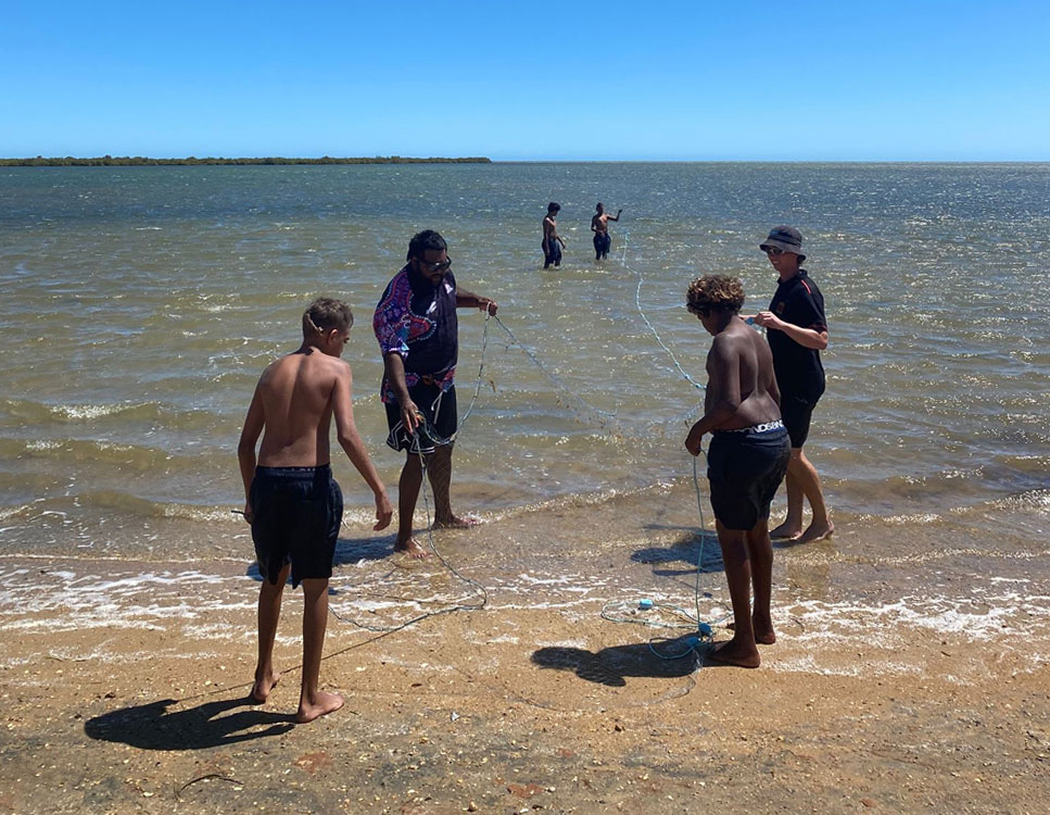 Participants of the Bush Classrooms in the shallows working together to coordinate fishing nets