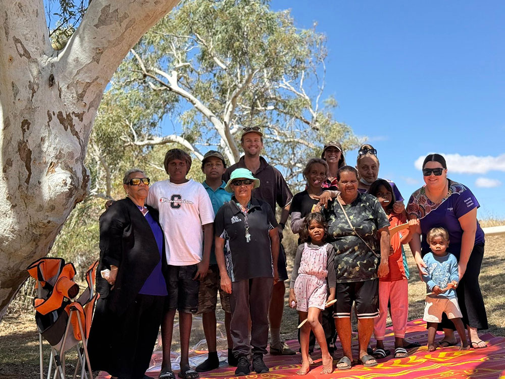 Young and old participants of the Bush Classrooms posing for the camera under a large eucalyptus gum tree