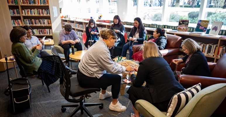 A group of people take part in a First Nations weaving exhibition.
