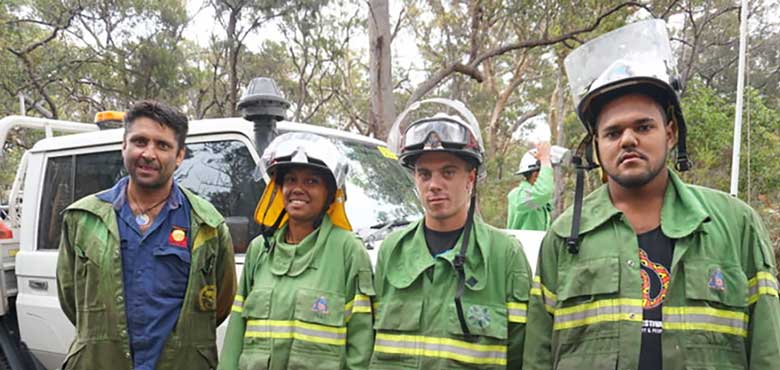 Four Quandamooka Rangers in firefighting uniform standing in front of a four wheel drive