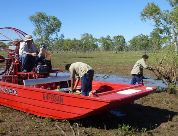 Three Indigenous rangers using a red airboat on Lake Argyle