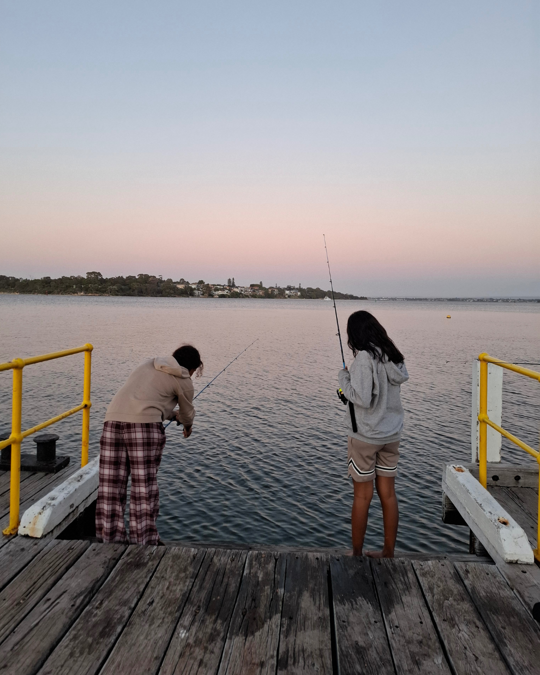 Two people fishing off a jetty.