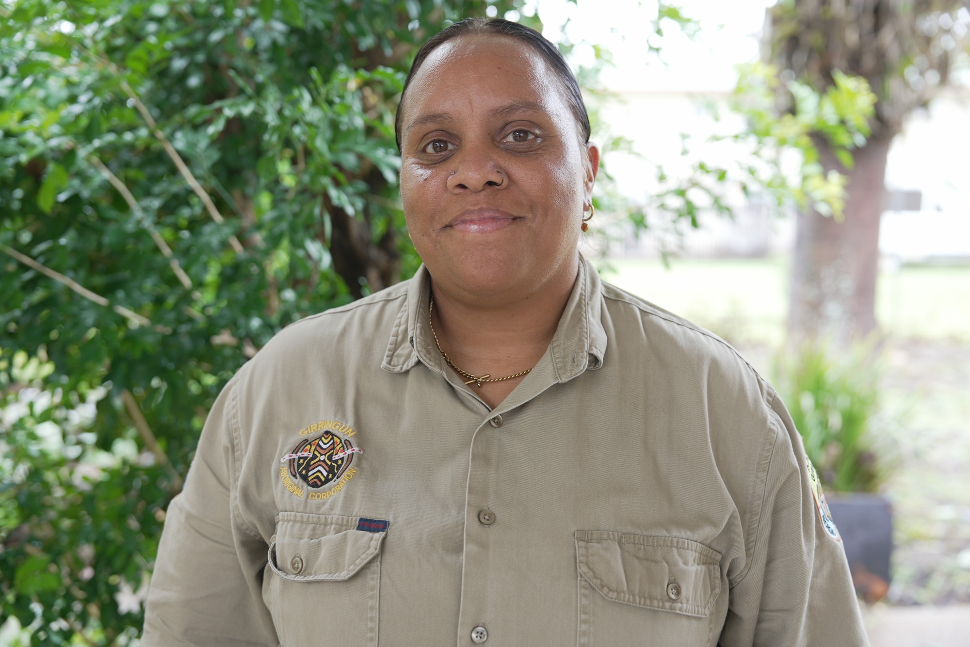 A woman stands in front of a bush