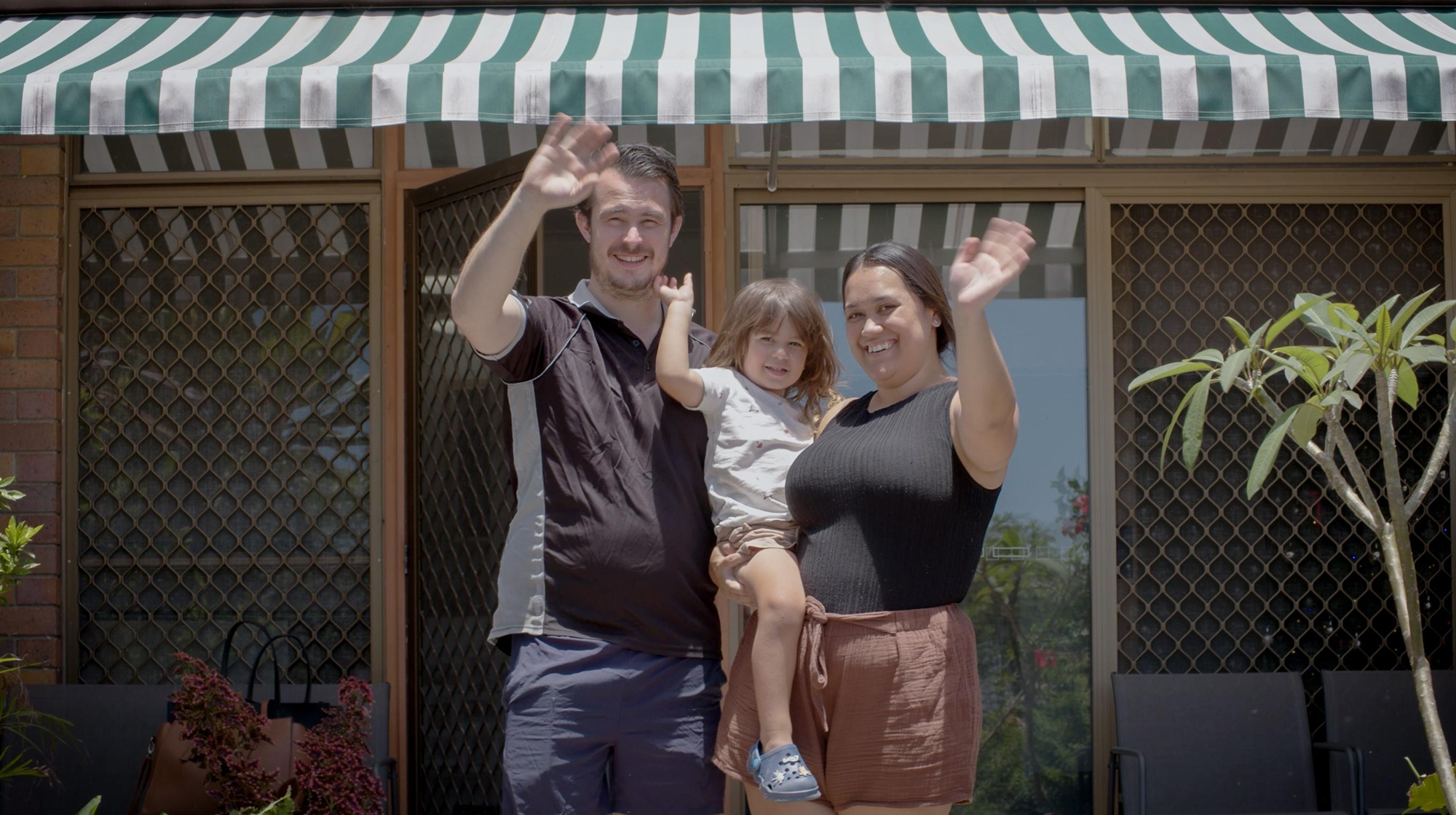 Two people stand in front of a house