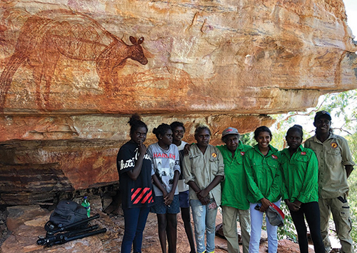 Eight young Daluk rangers standing in front of a rock art site