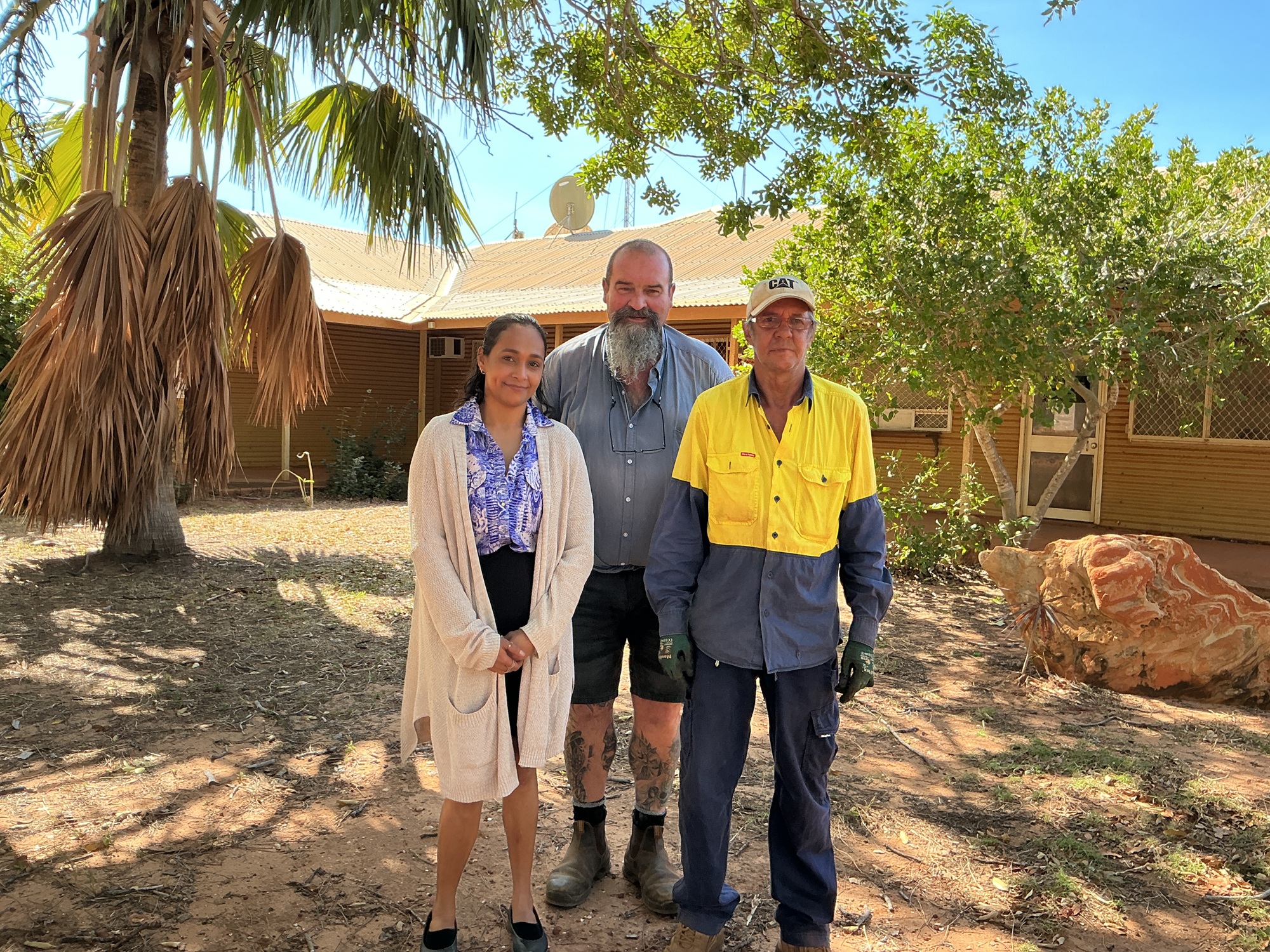 three people stand in front of a house