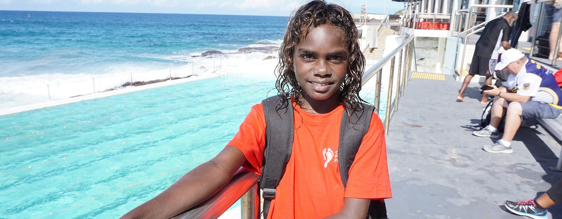 Indigenous boy smiling to camera, with a coastline in the background
