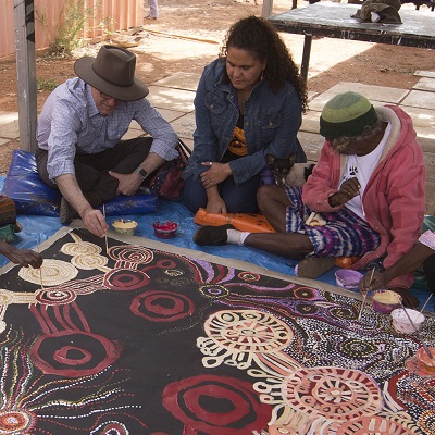The Prime Minister sitting and painting with members of an Indigenous community