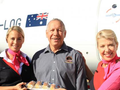 Dreamtime Tuka founder standing with flight crew, holding some Dreamtime Tuka food, in front of a plane