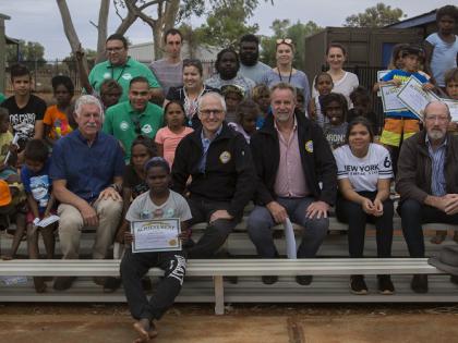 Photo of Indigenous participants and leaders sitting on outdoor stadium seating with the Prime Minister and Minister for Indigenous Affairs