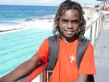 Indigenous boy smiling to camera, with a coastline in the background