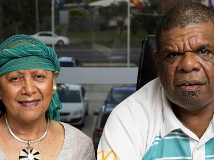 A female and male member of the Indigenous Wellbeing Centre, sitting together with an IWC brochure in front of them