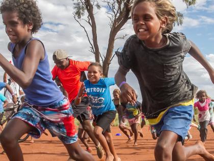 A large group of Indigenous children running fast