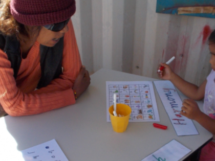 Indigenous children sitting at a desk with an early learning educator