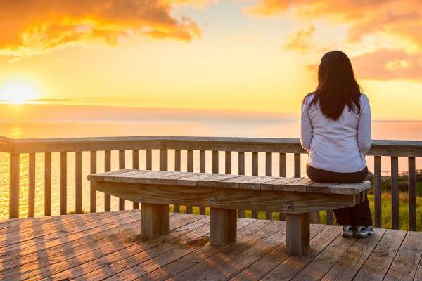 Person sitting on a bench watching a sunset