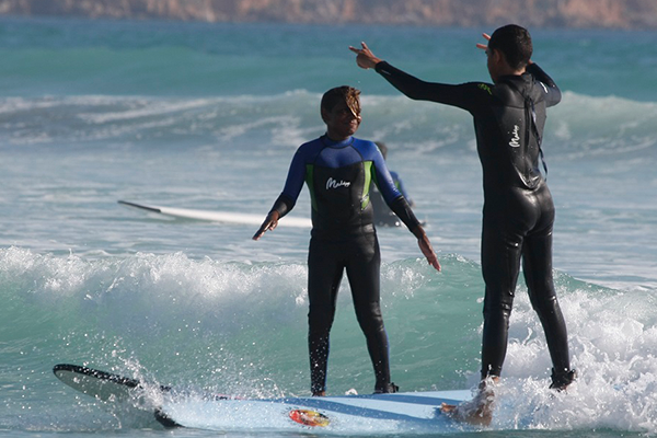 Two indigenous youths surfing on a beach