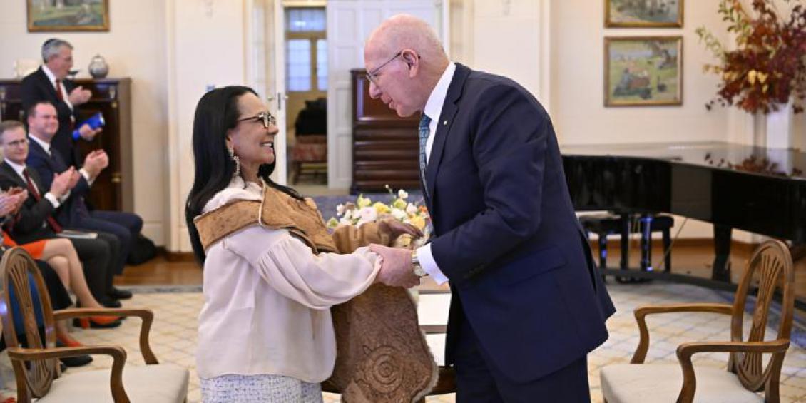 Image of The Hon Linda Burney MP with His Excellency General the Honourable David Hurley AC DSC (Retd) being sworn in at Government House. Minister Burney is wearing a kangaroo skin cloak over her shoulders. Image courtesy of the Department of Parliamentary Services, AUSPIC.