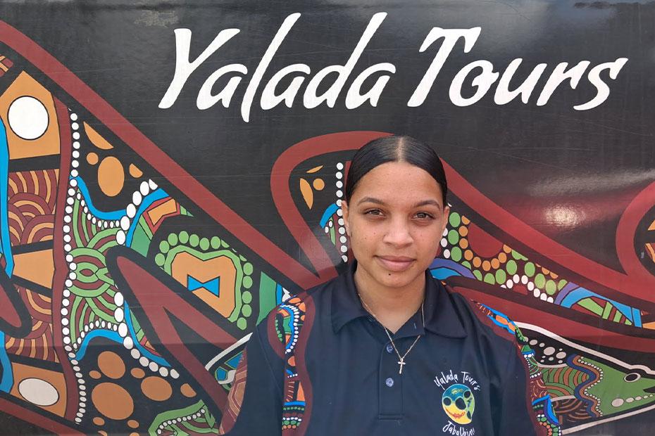 Young, female employee in front of a tour bus